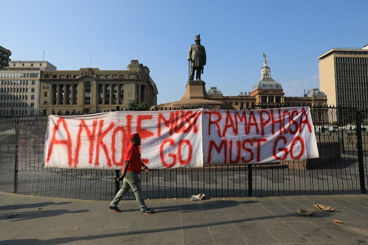 A sign "Ramaphosa must go" is displayed on the fence in Pretoria Church Square.