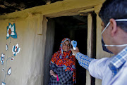 A healthcare worker checks the temperature of a shepherd girl at her hut during a Covid-19 vaccination drive at a forest area in south Kashmir's Pulwama district June 7, 2021. 