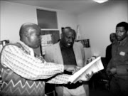 YOU'RE UNDER ARREST: Provincial coordinator of the stock theft unit Superintendent Alpheus Mokale, left, shows the suspected cattle thief inspector, middle, a warrant for his arrest. 19/05/2009. Pic. Alex Matlala. © Sowetan.