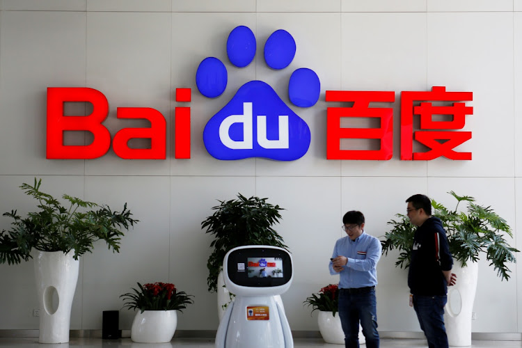 Men interact with a Baidu robot near the company logo at its headquarters in Beijing, China, April 23 2021. Picture: REUTERS/FLORENCE LO