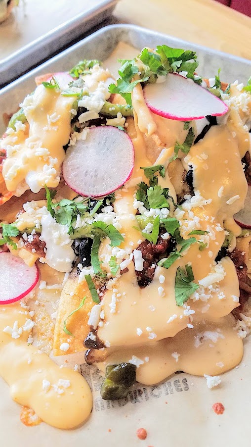 Bunk Bar at Water Ave, evenings only you can get Nachos with Queso Oaxaca, nacho cheese sauce, avocado salsa, chipotle salsa, black beans, roasted chilies, pickled jalapenos, cotija & sour cream