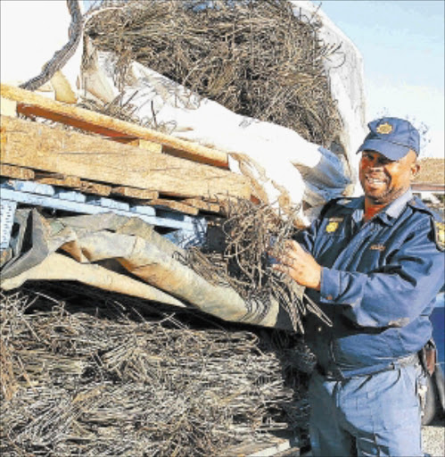 BOOTY: Constable Paul Disenyane displays 600kg of stolen copper cable that was recovered. Photo: The Herald