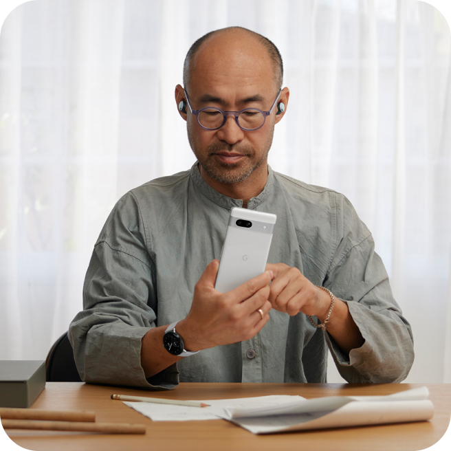 A man using a Google Pixel 7a phone in his office.