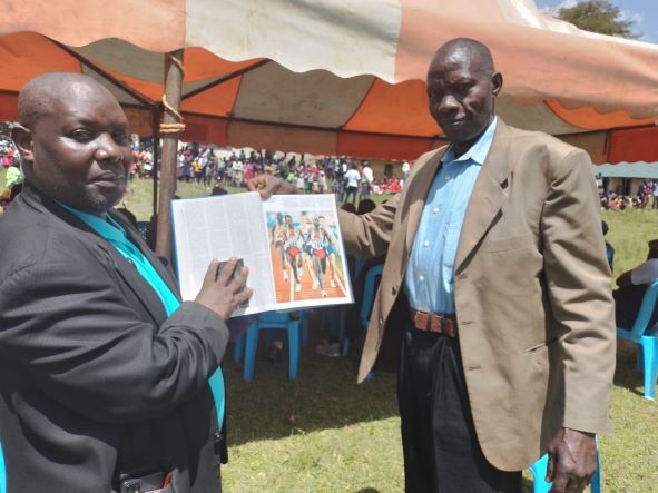 Paul Kimutai Ruto (R) displays the 1993 Stuttgart results book and showing his photo to Kipchumba Saina (L)