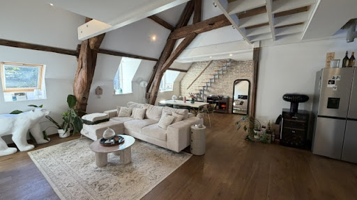 Living room with exposed beams and beige sofa in this luxury apartment / penthouse for sale in Dijon ($411,848 - 87 m²)