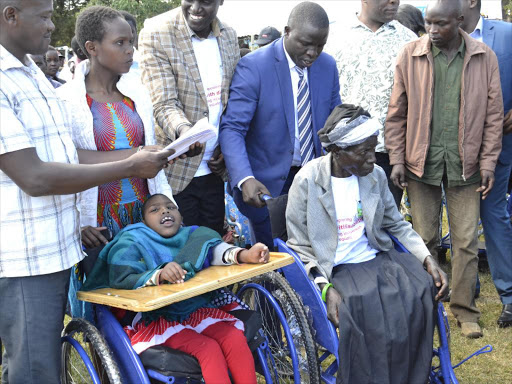 Nandi governor Stephen Sang (in blue suit) distributes wheelchairs in Kapsabet on Monday /BARRY SALIL