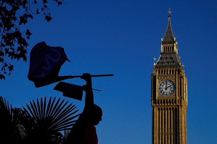 A Royal Mail worker holding flags is silhouetted as members strike over pay and conditions, outside of the Houses of Parliament in London, Britain, in this December 9 2022 file photo. Picture: REUTERS/TOBY MELVILLE