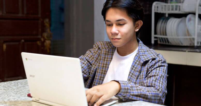 A male student using his Chromebook at home.