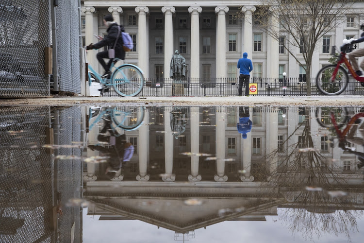 Pedestrians and cyclists pass the US treasury building in Washington, DC on April 10 2022. Picture: BLOOMBERG/TOM BRENNER