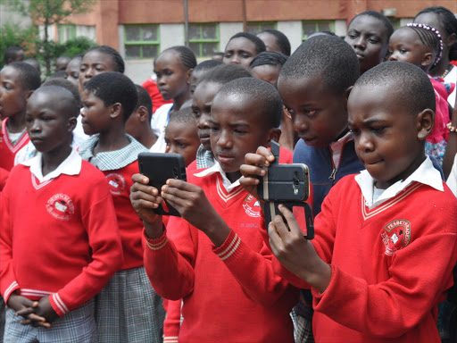 Fesbeth Academy pupils Brandline Shikami and John Owino take photos during an entertainment session at the school’s AGM in Kakamega on November 5 last year / SAMUEL SIMITI