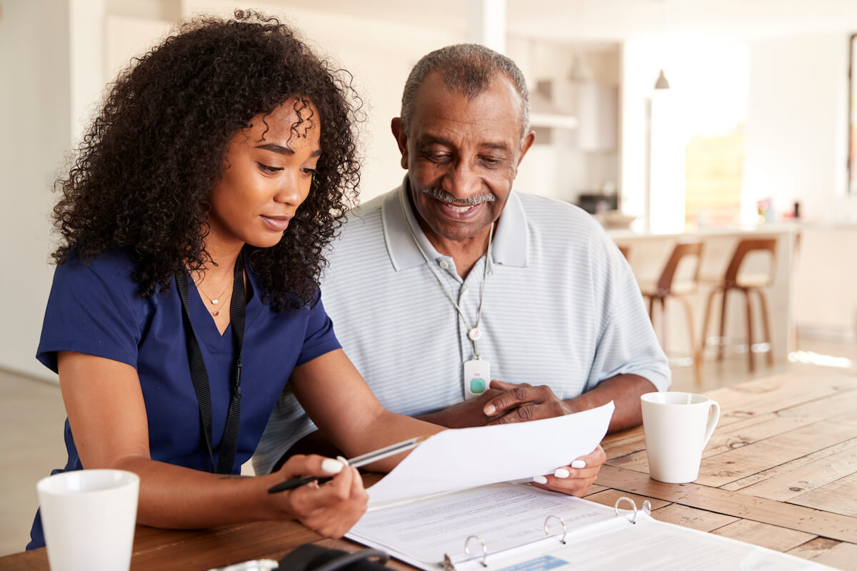 Mobile workforce management solutions: health worker and a senior man reading some documents