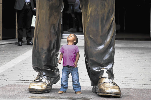 TRUE GIANT: Three-year-old Otlile Monama at the feet of a statue of Nelson Mandela in Sandton, Johannesburg