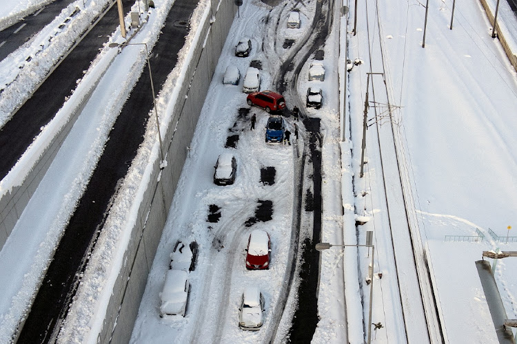 Firemen plough snow around a car as abandoned vehicles are covered in snow on the Attiki Odos motorway, following heavy snowfall in Athens, Greece, January 25, 2022.