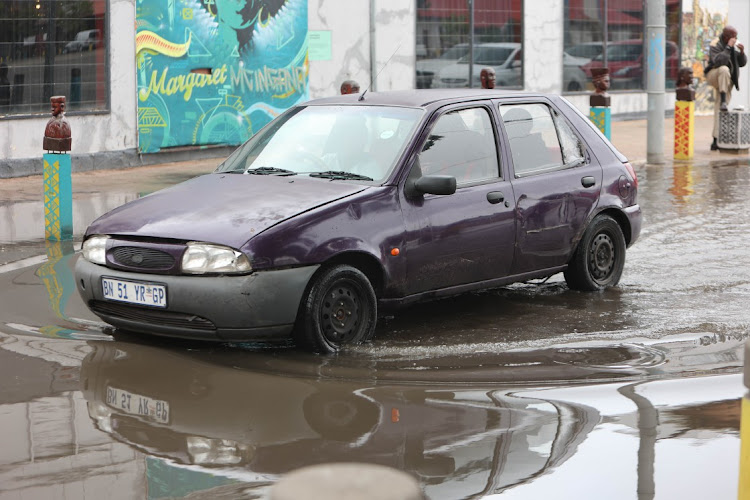 A car makes its way through a flooded road in Newtown.