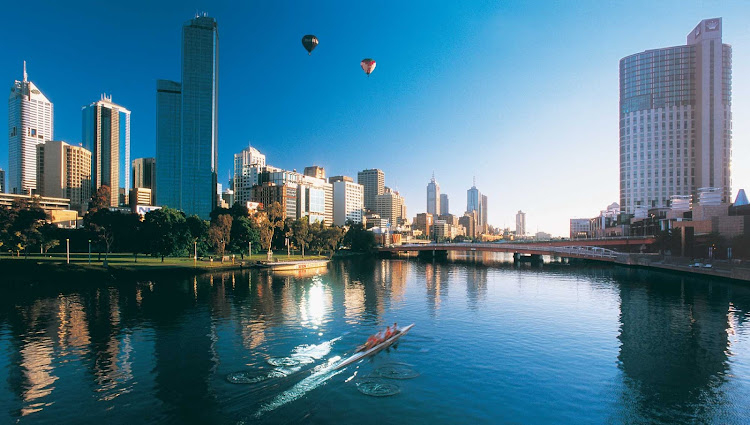 Rowers and hot air balloons over the Melbourne skyline and Yarra River.