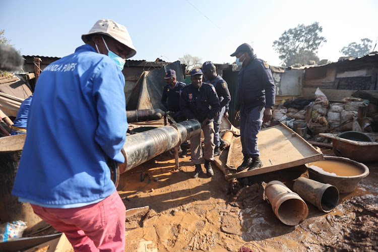 Police members remove gas canisters from the Angelo informal settlement in Boksburg, where 17 people died after gas leaked from a nitrate oxide canister used by illegal miners to refine their product into gold. Picture: Alaister Russell