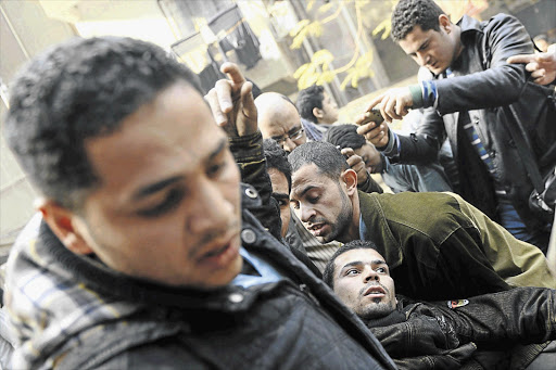 RISE IN BODY COUNT: Supporters of the Muslim Brotherhood and of ousted Egyptian president Mohamed Morsi carry a demonstrator shot in clashes with security forces in Cairo on the third anniversary of the Egyptian uprising against Hosni Mubarak