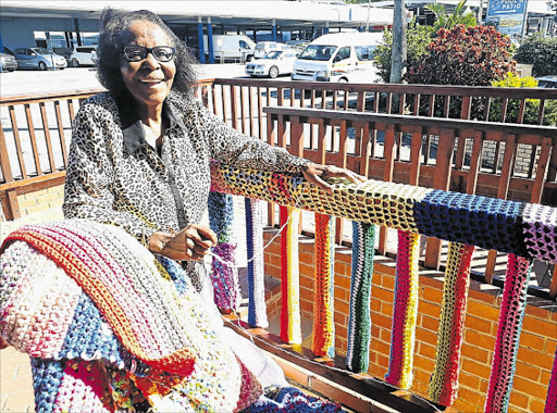 CRAFT ACTIVIST: Crafter Caroline Bacela, 77, has crocheted 35m of colourful wool around the railings outside the Eastern Cape Craft Collection shop in Old Transkei Road, in a yarn-bombing exercise to draw attention to supporting local crafters Picture: BARBARA HOLLANDS