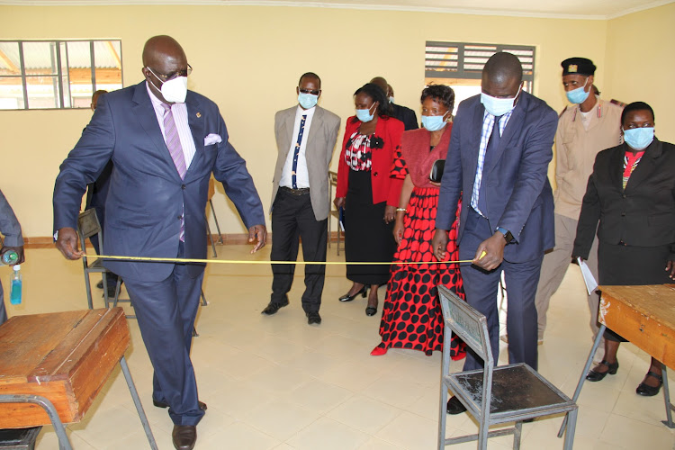 Education CS George Magoha use tape to measure for himself the social distance required in a class room for learners at Asumbi TTC in Rangwe constituency on July18,2020