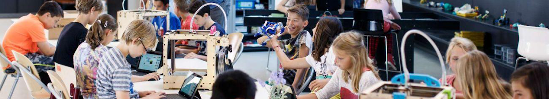 Several kids working with tablets and printers in a classroom setting