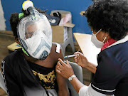 A doubly masked Capetonian receives the Covid-19 vaccine at the Hope Exchange. While the national health department thinks about how to register undocumented people for the vaccine, the Western Cape is rolling out jabs.