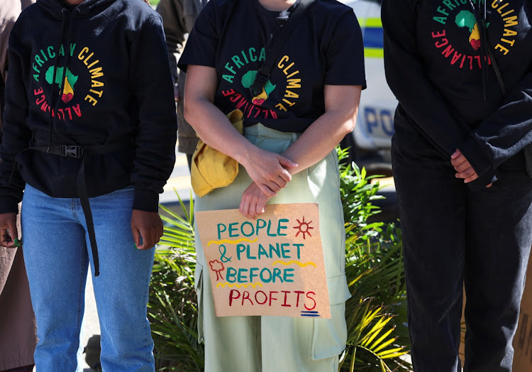 A climate activist holds a placard as people call for climate justice resistance against oil and gas corporations and to end fossil fuels outside the Cape Town International Convention Centre during the Southern Africa Oil and Gas Conference in Cape Town, South Africa , September 13, 2023.