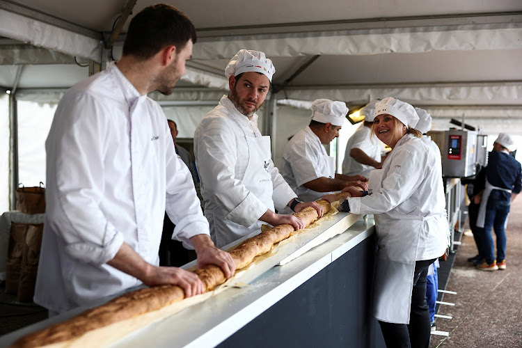 French bakers stand near a large rotating oven in an attempt to beat the world record for the longest baguette during the Suresnes Baguette Show in Suresnes near Paris, France.