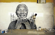 Nelson Tavares, 24, works on a mural of Nelson Mandela in his neighbourhood in Lisbon, Portugal. Mandela was yesterday discharged from hospital after almost three months of being treated for a lung infection.