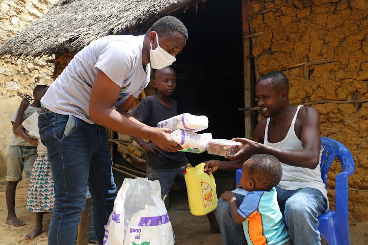 Mwachiro Mwandodo get his relief food from Suleiman Ngala at Mtomondnoni Scheme A on Friday.
