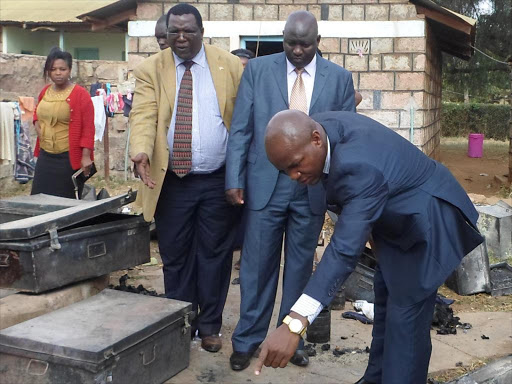 ASSESSING THE DAMAGE: Yatta education officer Elkana Nyaga (in brown court) and MP Francis Mwangangi (bending) at Matuu Memorial Girls High School on July 26, 2015, after a night fire. Looking on is an unidentified education officer. Photo/Andrew Mbuva