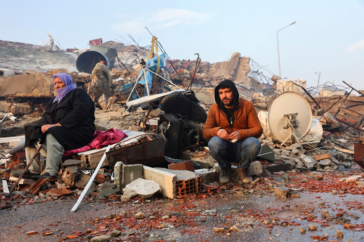 People sit amid rubble following an earthquake in Hatay, Turkey, in this photo taken on February 7 2023. Picture: REUTERS/UMIT BEKTAS