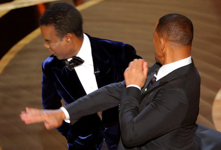 Will Smith (R) hits Chris Rock as Rock spoke on stage during the 94th Academy Awards in Hollywood, Los Angeles, California, U.S. on March 27, 2022.