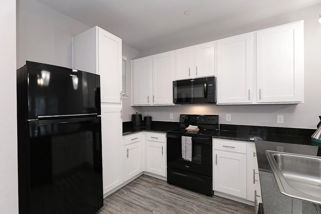 Fully-equipped kitchen with wood-inspired flooring, white cabinets, and stainless steel appliances