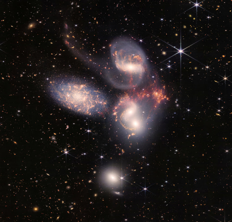 A group of five galaxies that appear close to each other in the sky - two in the middle, one toward the top, one to the upper left, and one toward the bottom - in a mosaic or composite of near and mid-infrared data from Nasa's James Webb Space Telescope.