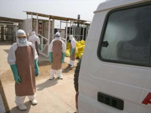 Healthcare workers prepare to disinfect an ambulance transporting a newly admitted Ebola patient at the entrance to the Save the Children Kerry Town Ebola treatment centre outside Freetown, Sierra Leone, December 22, 2014. /REUTERS