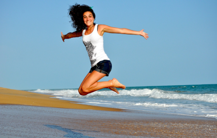 Girl jumping on the beach small promo image