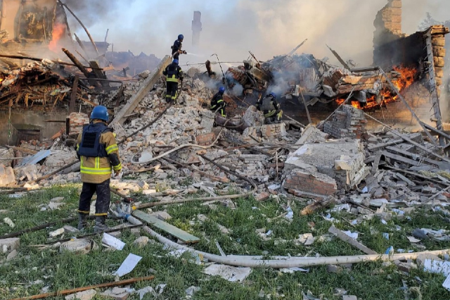 Emergency crew tend to a fire near a burning debris, after a school building was hit as a result of shelling, in the village of Bilohorivka, Luhansk, Ukraine, May 8, 2022.