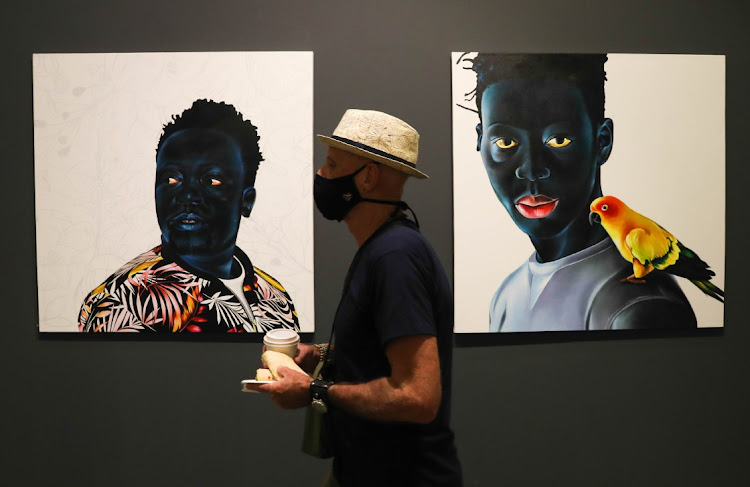 A visitor walks past Ley Mboramwe's artwork at the Investec Cape Town Art Fair at the Cape Town International Convention Centre.