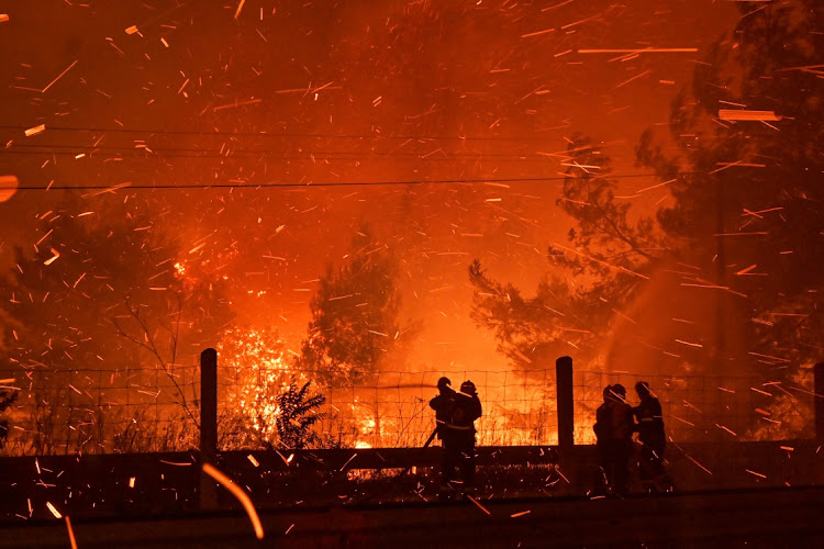 Firefighters try to put out a fire as flames spread over a highway during a wildfire on August 5 2021 in northern Athens, Greece.