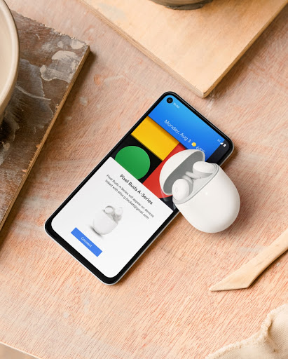 A Pixel phone on a table with Pixel Buds next to it.