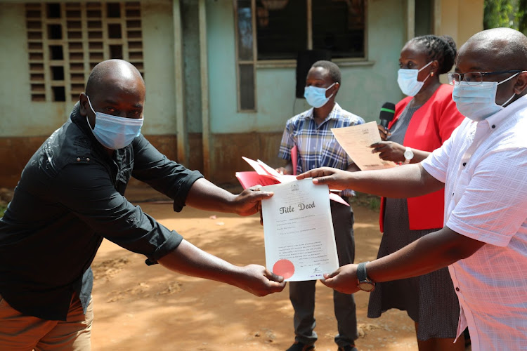 Principal Secretary, State Department for Housing and Urban Development Charles Hinga, issues tittle deed to a resident of Malindi one of the beneficiary for informal settlement schemes under KISIP in Malindi