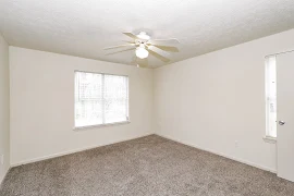 Bedroom featuring two windows, ceiling fan, and neutral colored carpet and walls