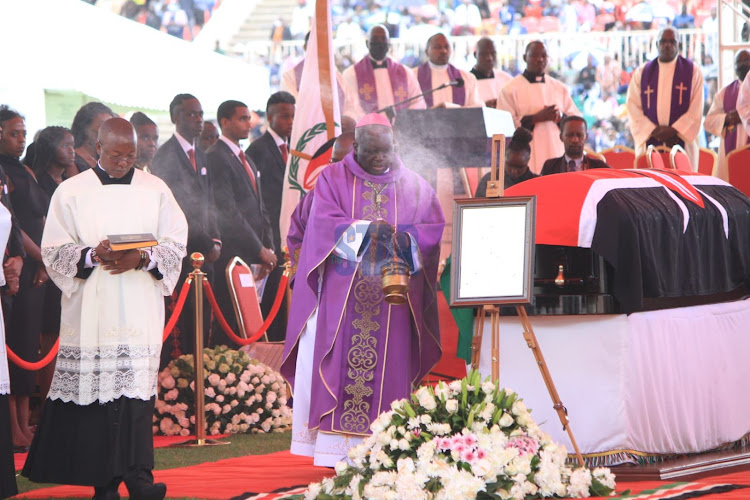 Archbishop Philip Anyolo of the Catholic Church blesses the body of the late President Mwai Kibaki at the start of his state funeral service at Nyayo National Stadium on April 29, 2022.