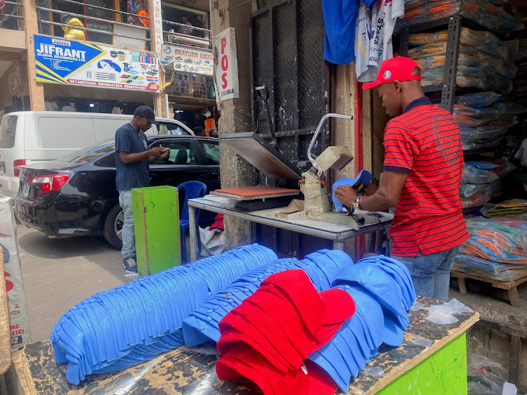 A worker prints on baseball caps at a printing shop in Abuja, Nigeria in February 2023.