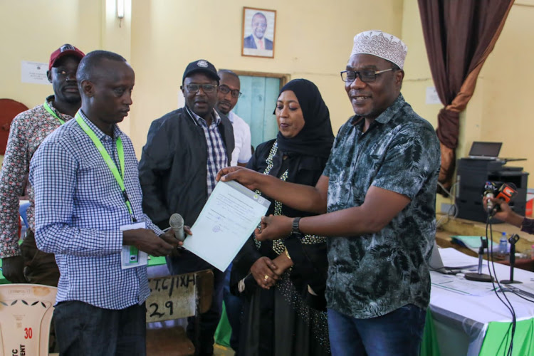 IEBC returning officer Ibrahim Wario Ali hands over a certificate to Rashid Bedzimba at the Kisauni tallying centre in Mombasa