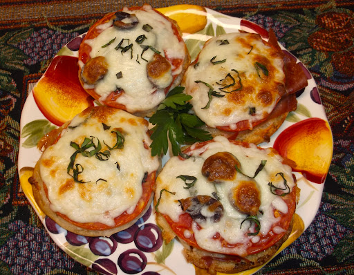 Plated tomato, basil, mozzarella and prosciutto on English muffin rounds.