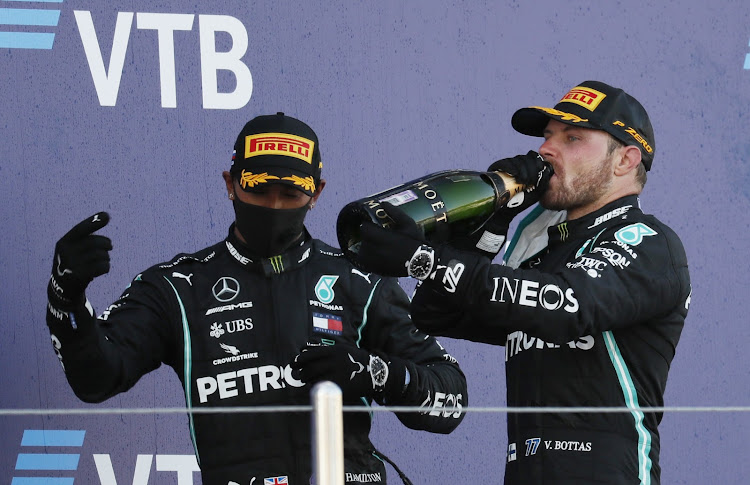 Mercedes' Valtteri Bottas celebrates with sparkling wine on the podium after winning the race alongside third placed Lewis Hamilton.