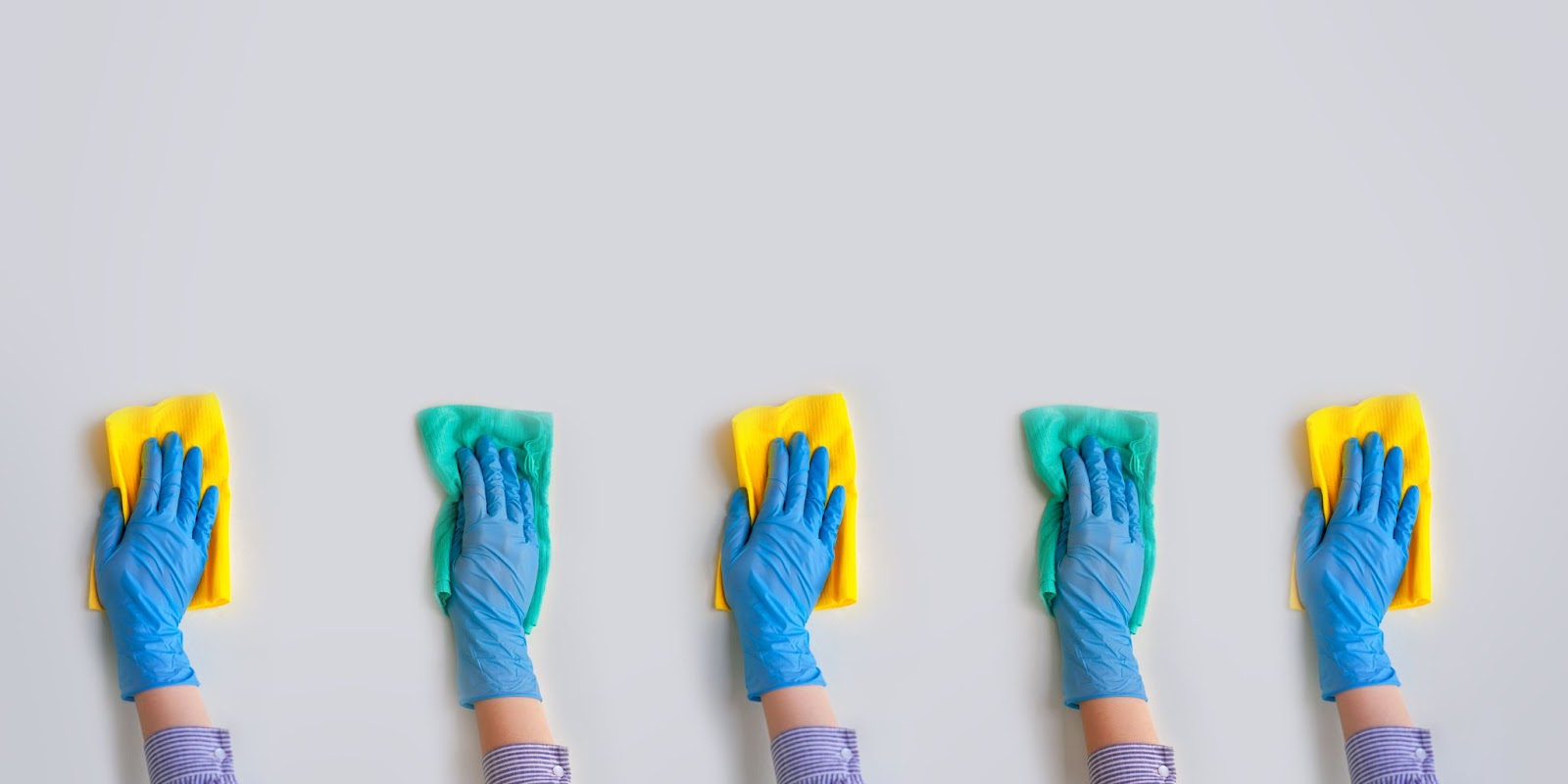 Five hands wrapped in gloves cleaning the surface with hand cloths