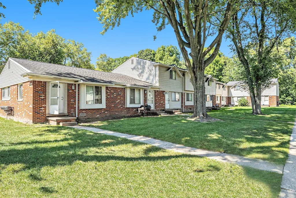 Carolina Flatz building exterior with warm brick and neutral siding with sidewalks to each door and shade trees nearby