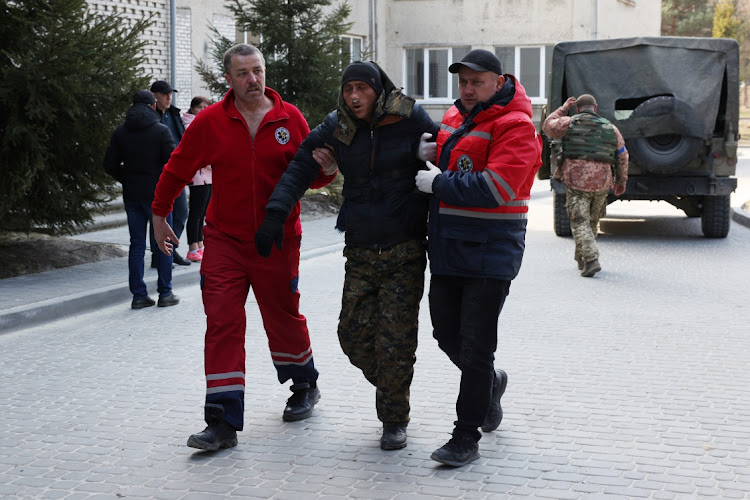 A patient is assisted by medical staff as he arrives at Novoiavorivsk District Hospital on March 13, 2022 in Novoiavorivsk, Ukraine. Early this morning, a series of Russian missiles struck the International Center for Peacekeeping and Security at the nearby Yavoriv military complex, killing at least nine and wounding dozens, according to Ukrainian officials. The site is west of Lviv and mere miles from Ukraine's border with Poland, a NATO member.